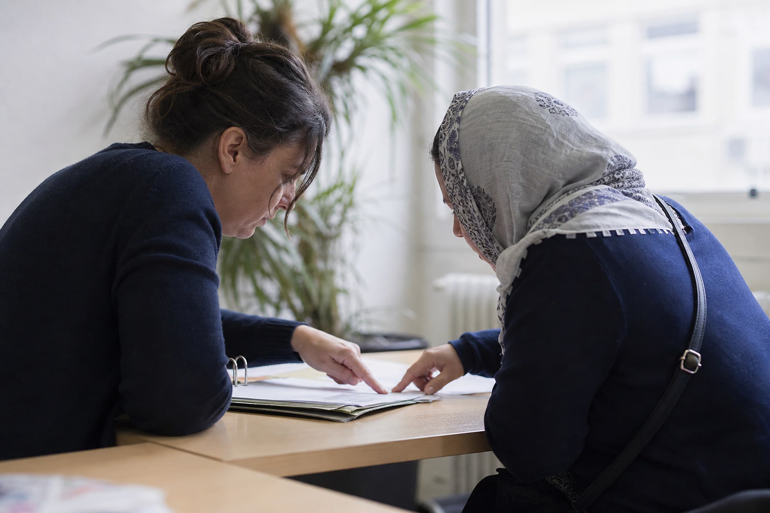 Beraterin und Ratsuchende gehen gemeinsam Unterlagen durch